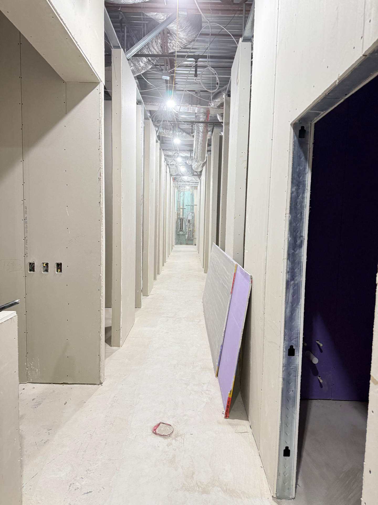 Finished drywall corridor with hung walls and door openings ready for finishing