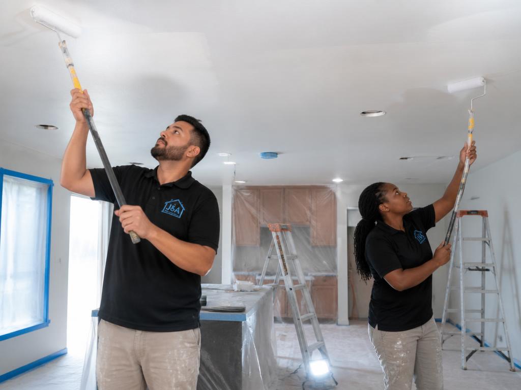Painter using an extension pole to paint a ceiling
